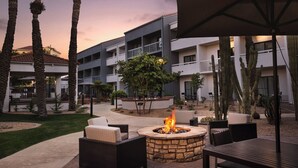 An outdoor patio area with a stone fire pit, seating, and cacti. - Courtyard by Marriott Phoenix Mesa (Mesa)