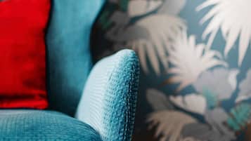 Ein Detailaufnahme eines hölzern-grünen Sofas mit strukturierter Stoffoberfläche und einem roten Kissen.