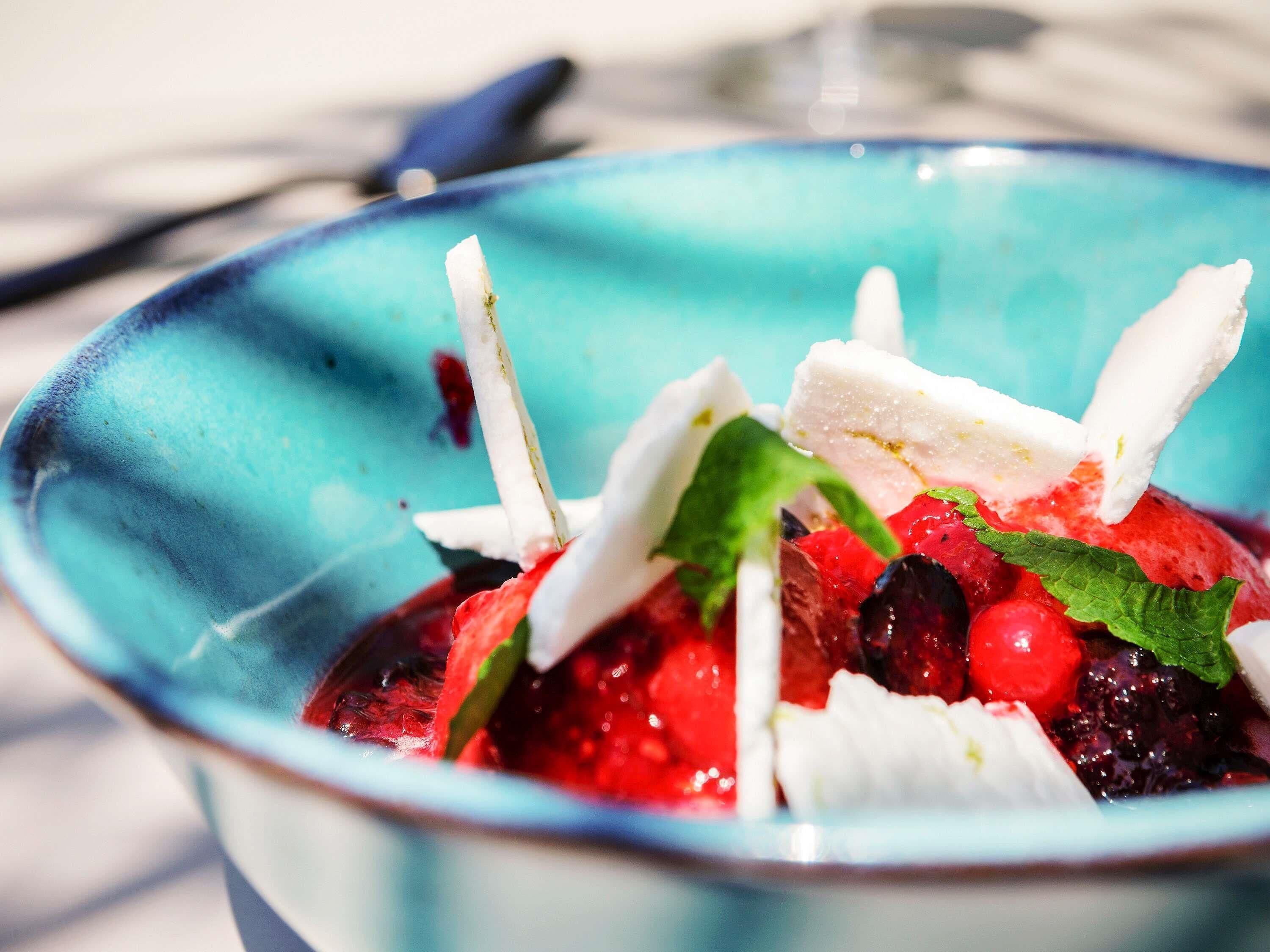 A bowl of fruit salad with berries and mint leaves.