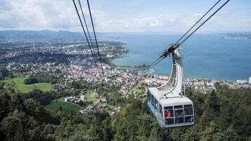 Un teleférico con pasajeros, mostrando vistas de un pueblo costero y vegetación circundante.