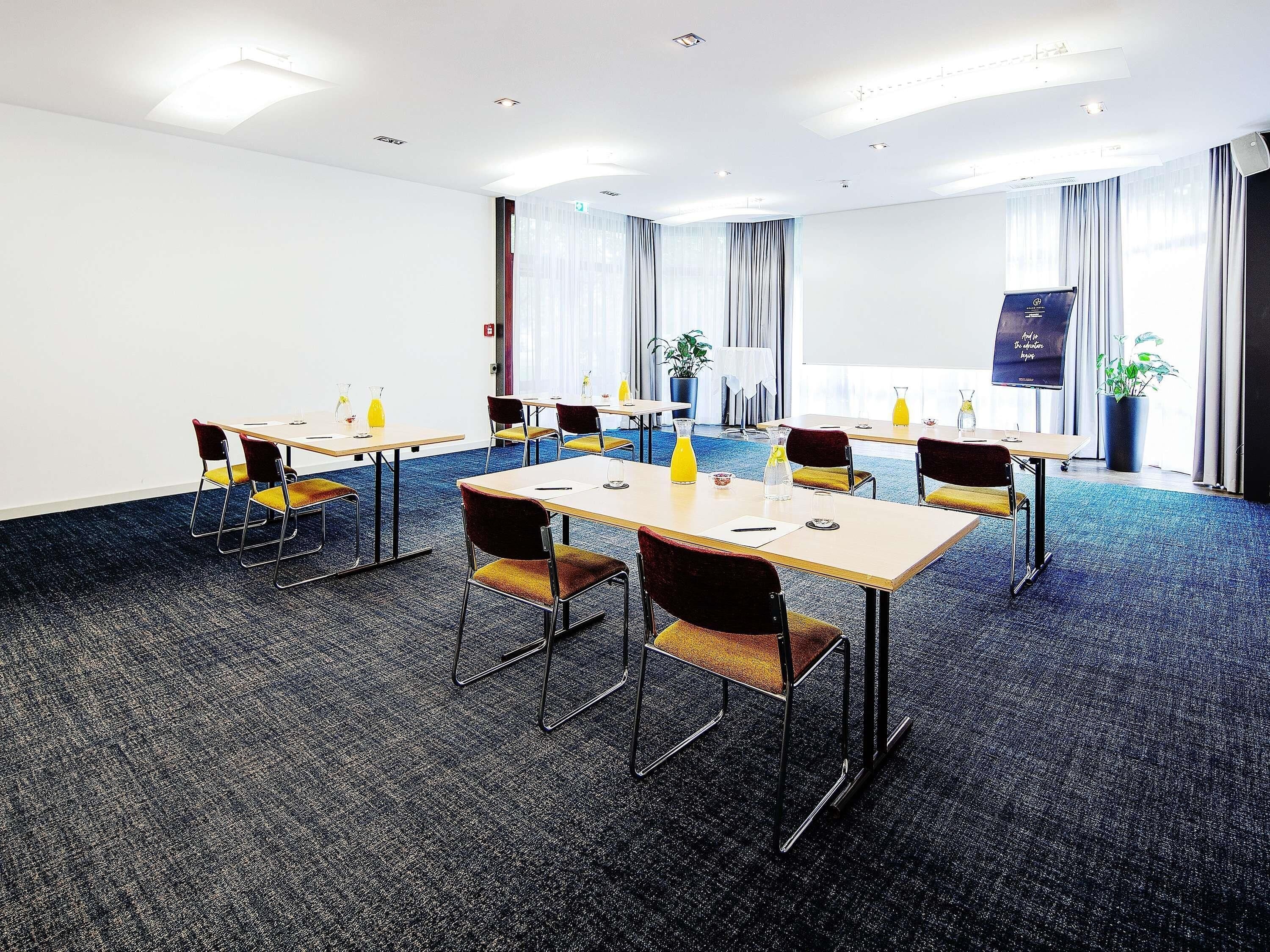 Een vergaderzaal met tafels, stoelen en een projectiescherm.