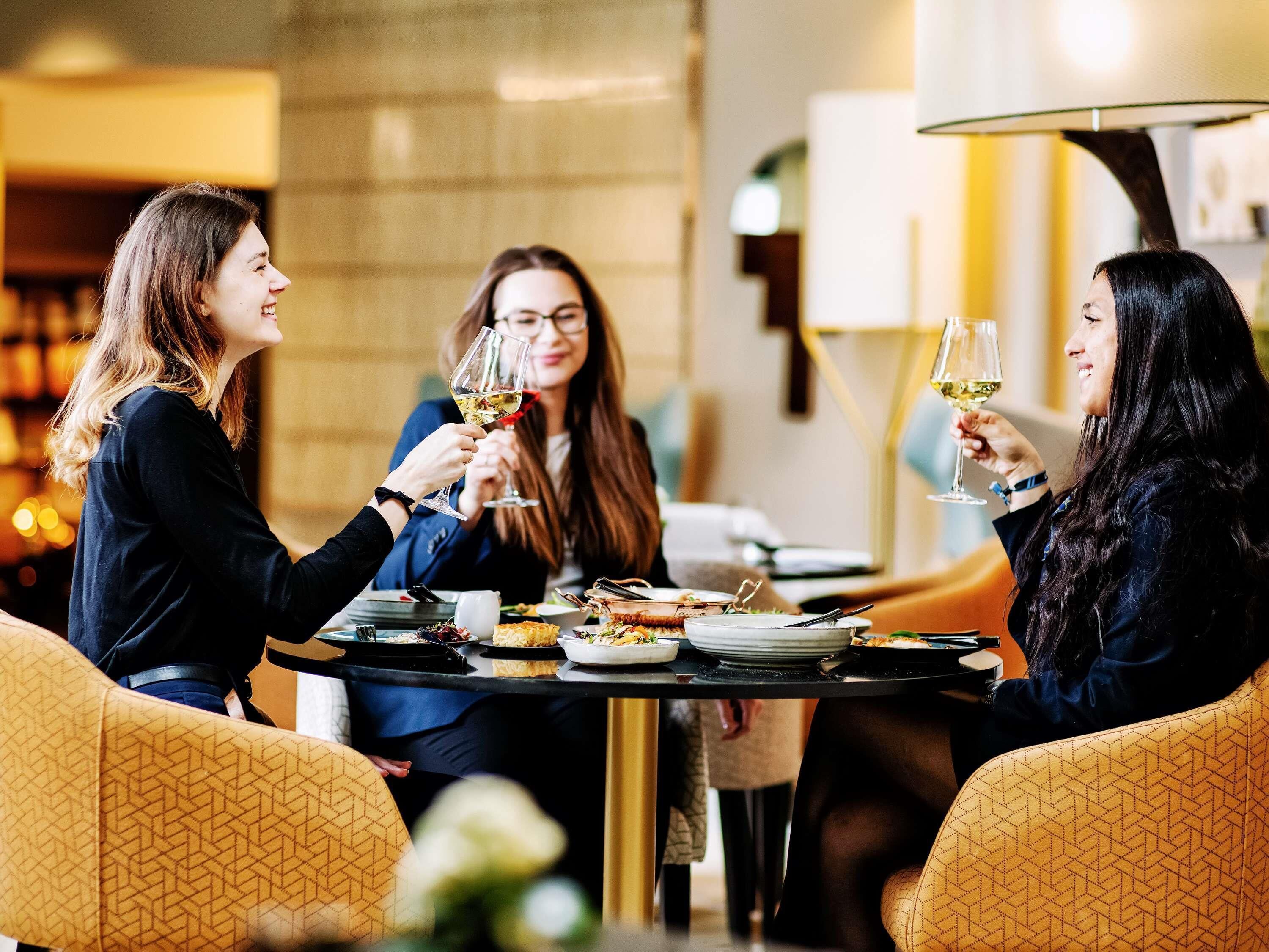 Un grupo de personas brindando con copas de vino alrededor de una mesa redonda en un ambiente cálido e interior.