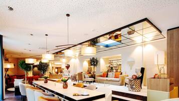 Eine moderne Hotelhalle mit einer langen Rezeption, mehreren Sitzbereichen und einem großen Spiegel, der den Raum widerspiegelt.
