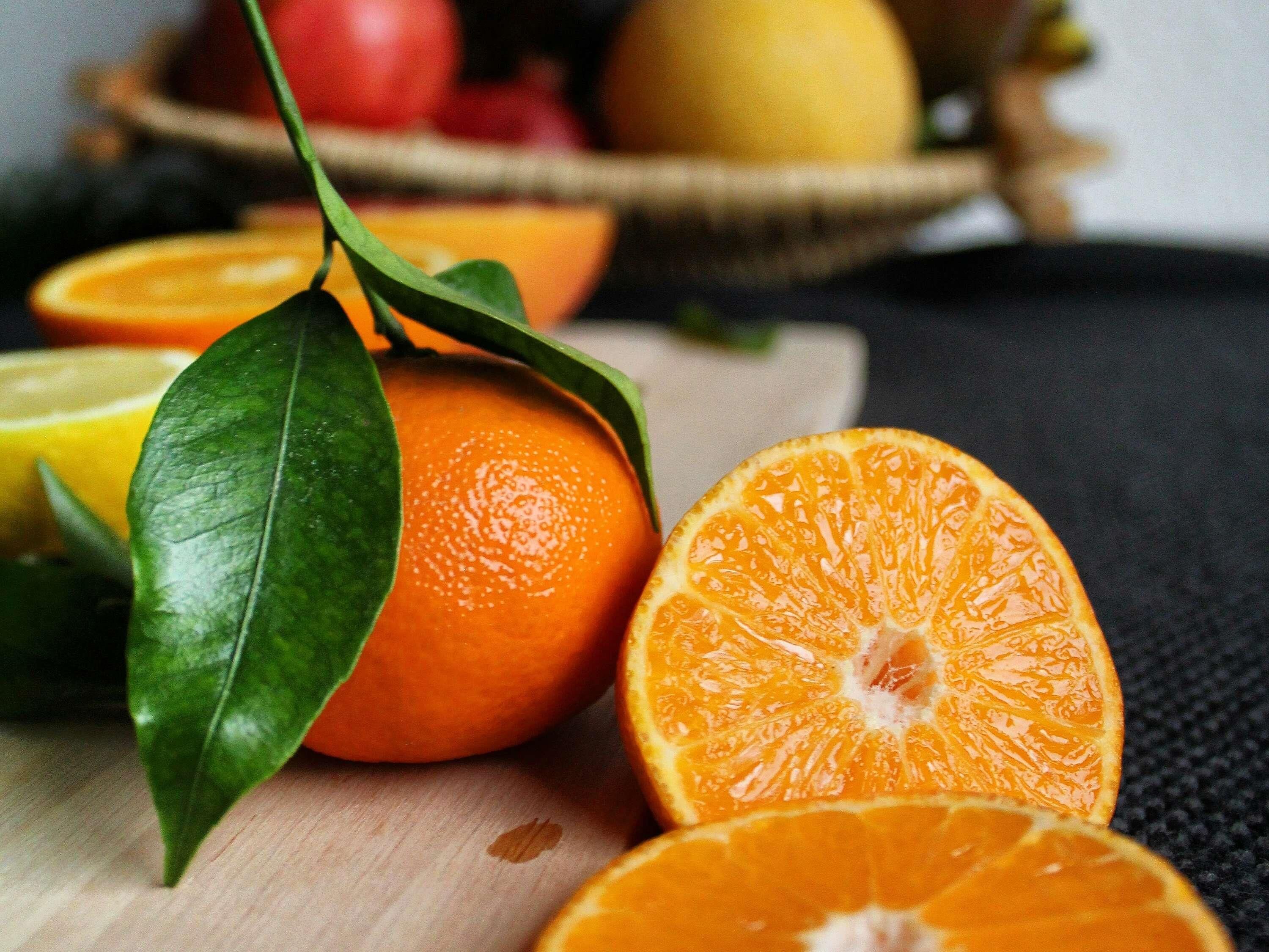 Naranjas y una hoja sobre una superficie de madera.