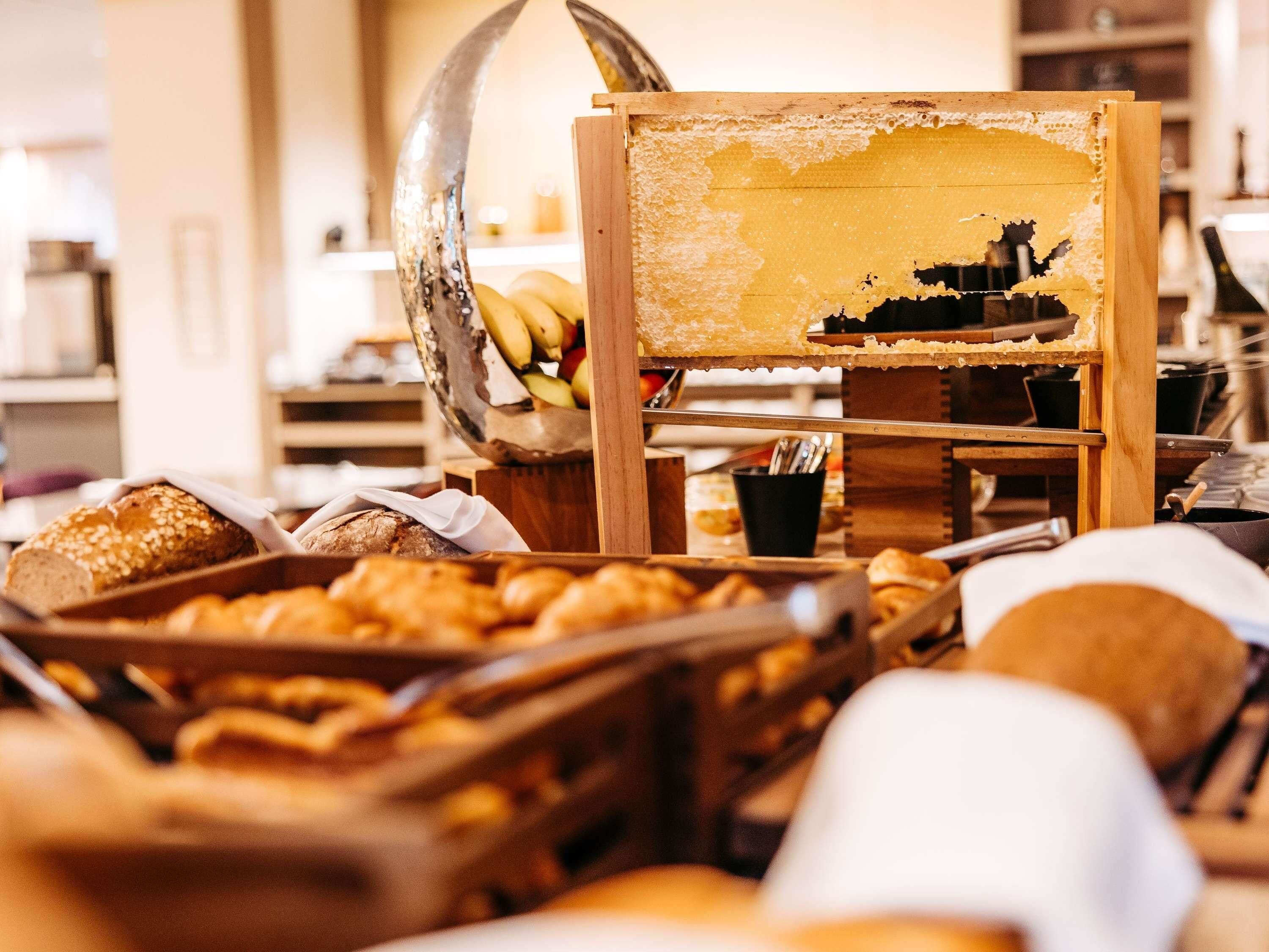 A bakery display with bread, pastries, and a honey dipper.