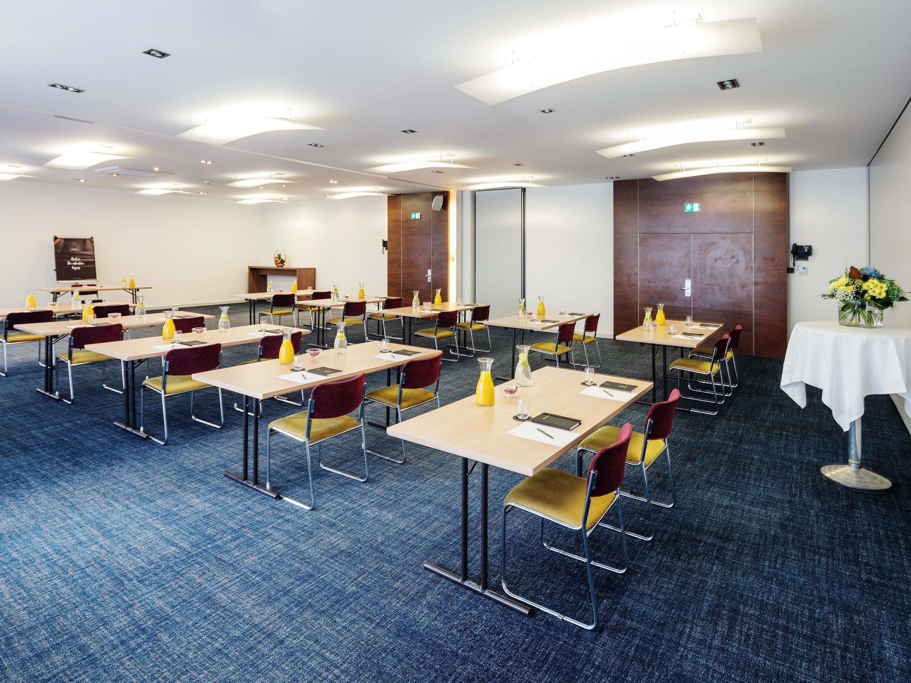 Une salle de conférence dotée de plusieurs tables et chaises, ainsi que de plaques nominatives et de bouteilles d’eau.