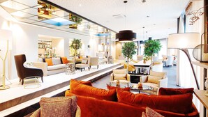 Un intérieur moderne comprenant un espace salon avec des canapés et des fauteuils, un coin repas et un escalier menant à un niveau supérieur.