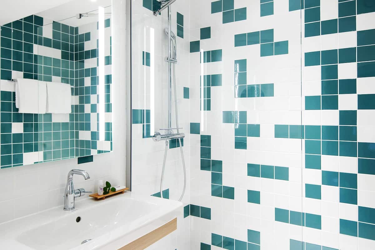 Ein Badezimmer mit einem weißen Waschbecken, einem Spiegel und einer Dusche mit Glastür.