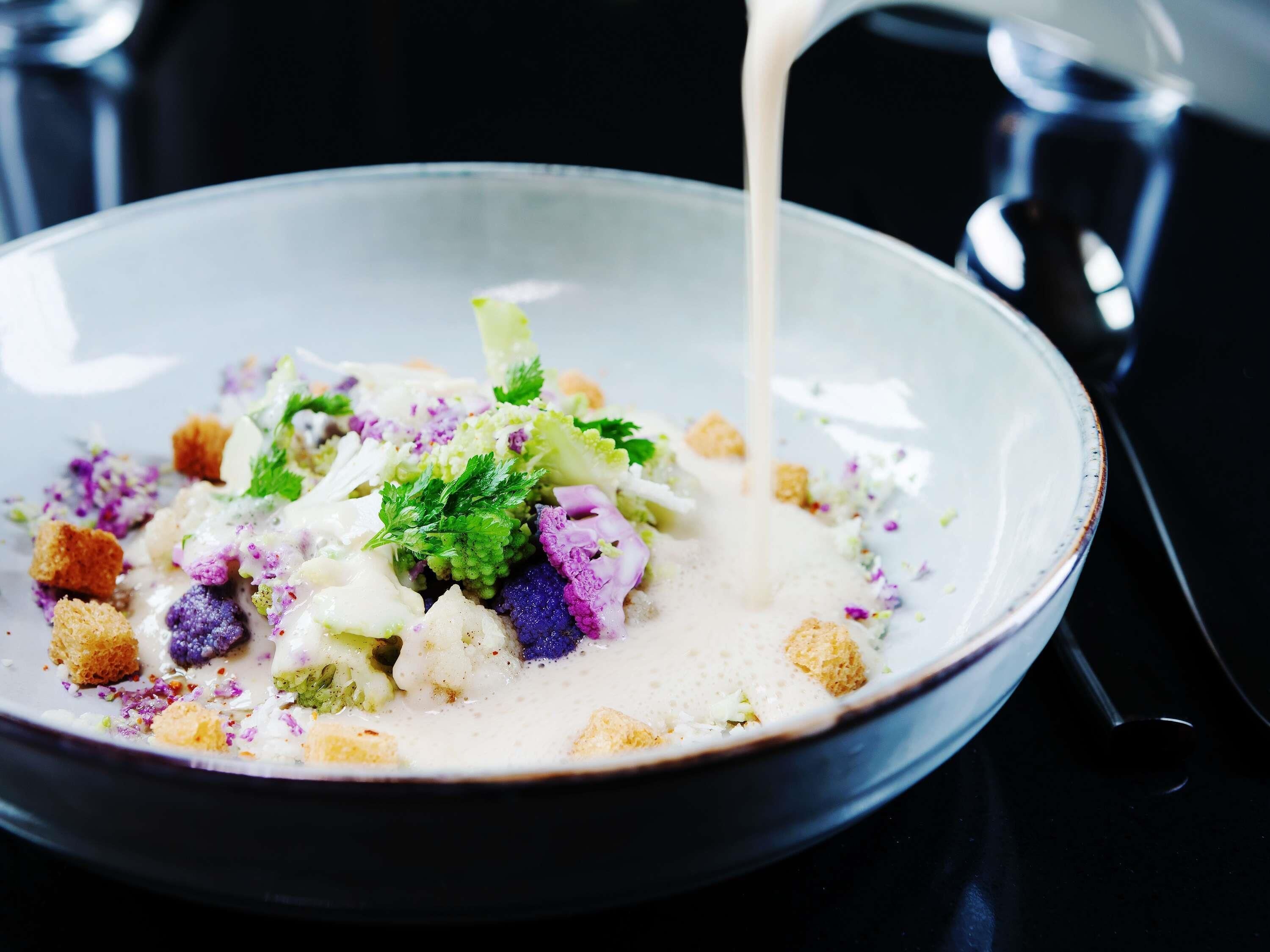 A bowl of colorful salad with croutons and a creamy dressing.