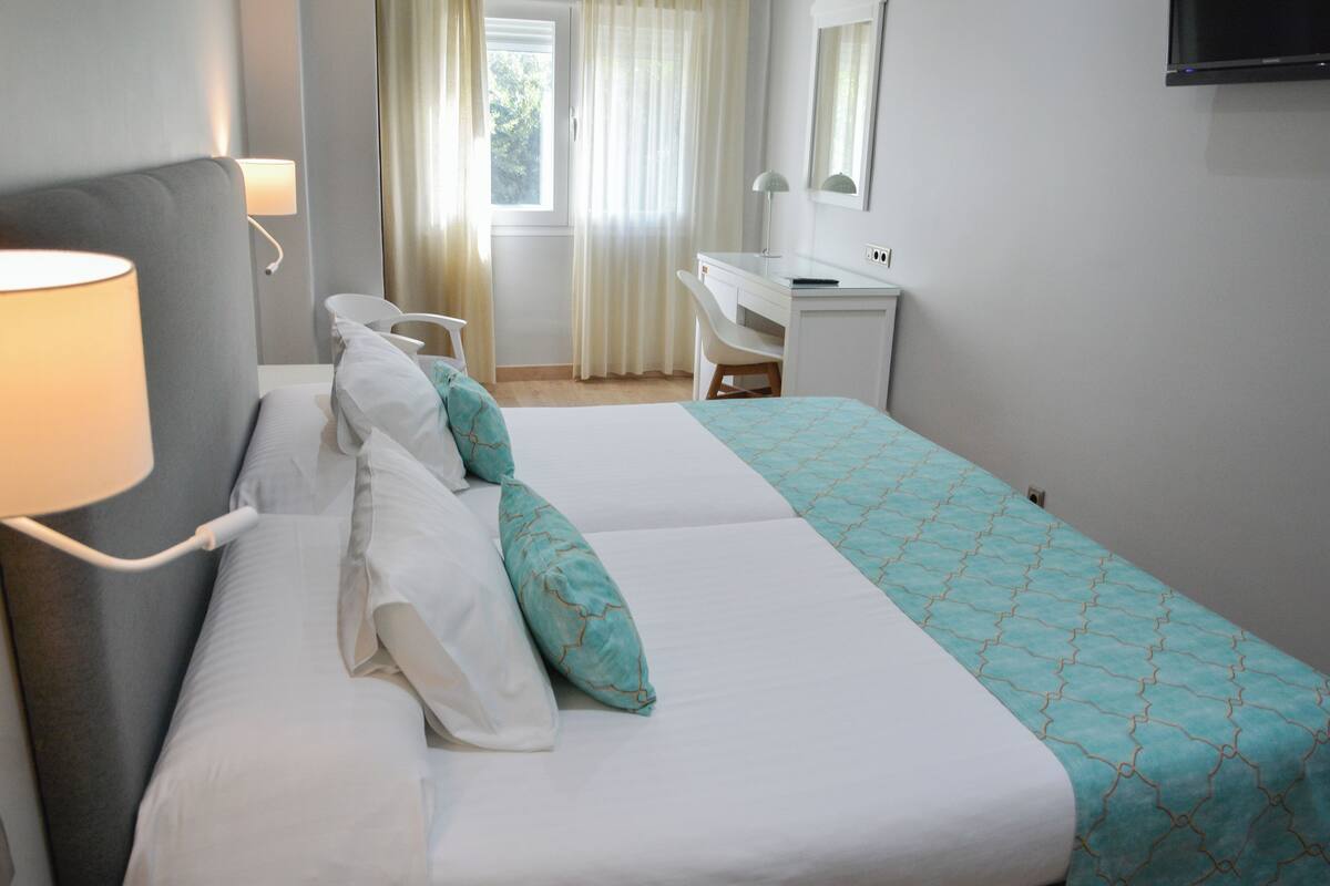 Una habitación de hotel con cama, escritorio, silla y televisor.