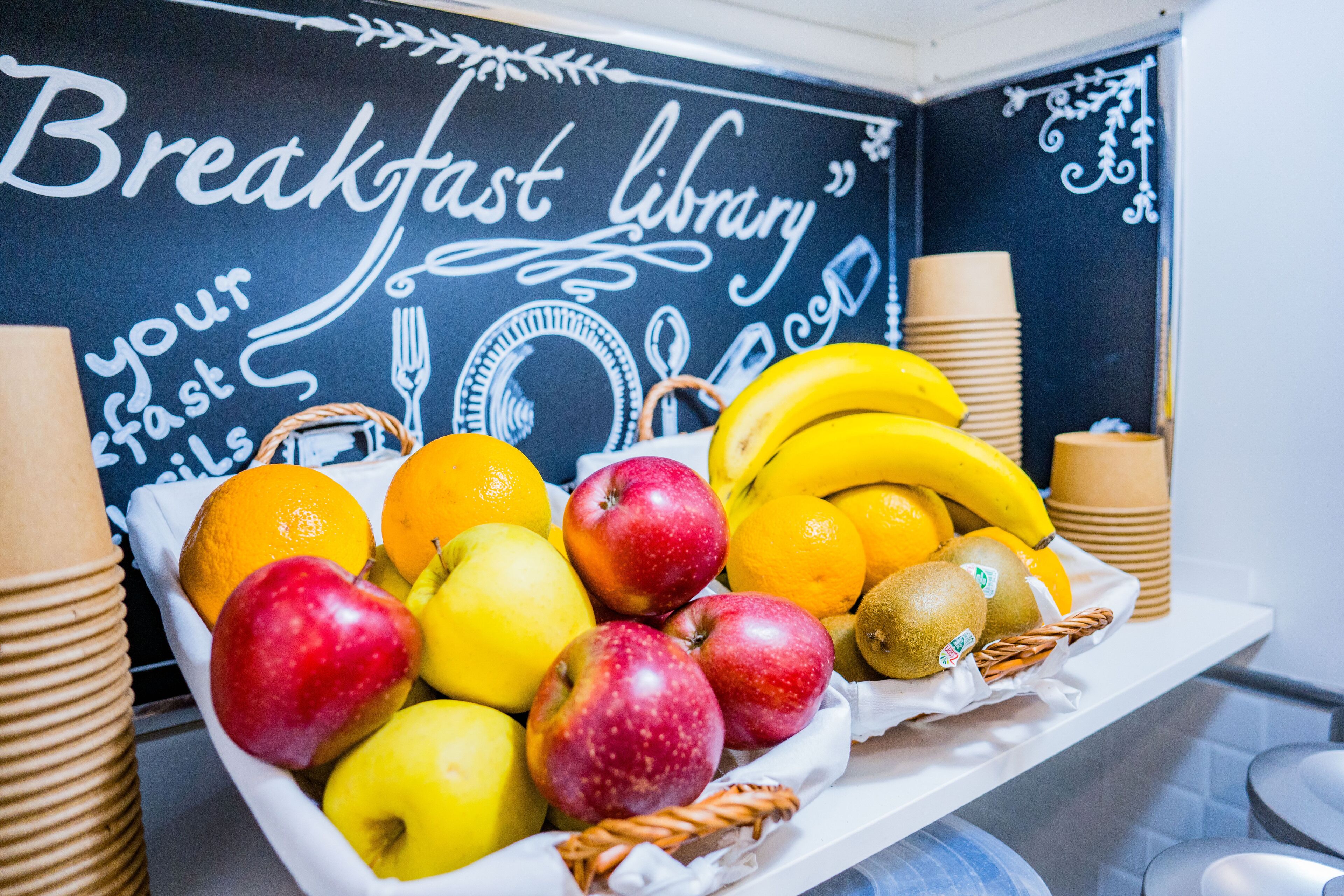 A breakfast tray with fruits and a chalkboard wall with the text "Breakfast library".