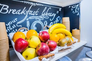 Una bandeja de desayuno con frutas y una pared de pizarra con el texto 'Breakfast library'.