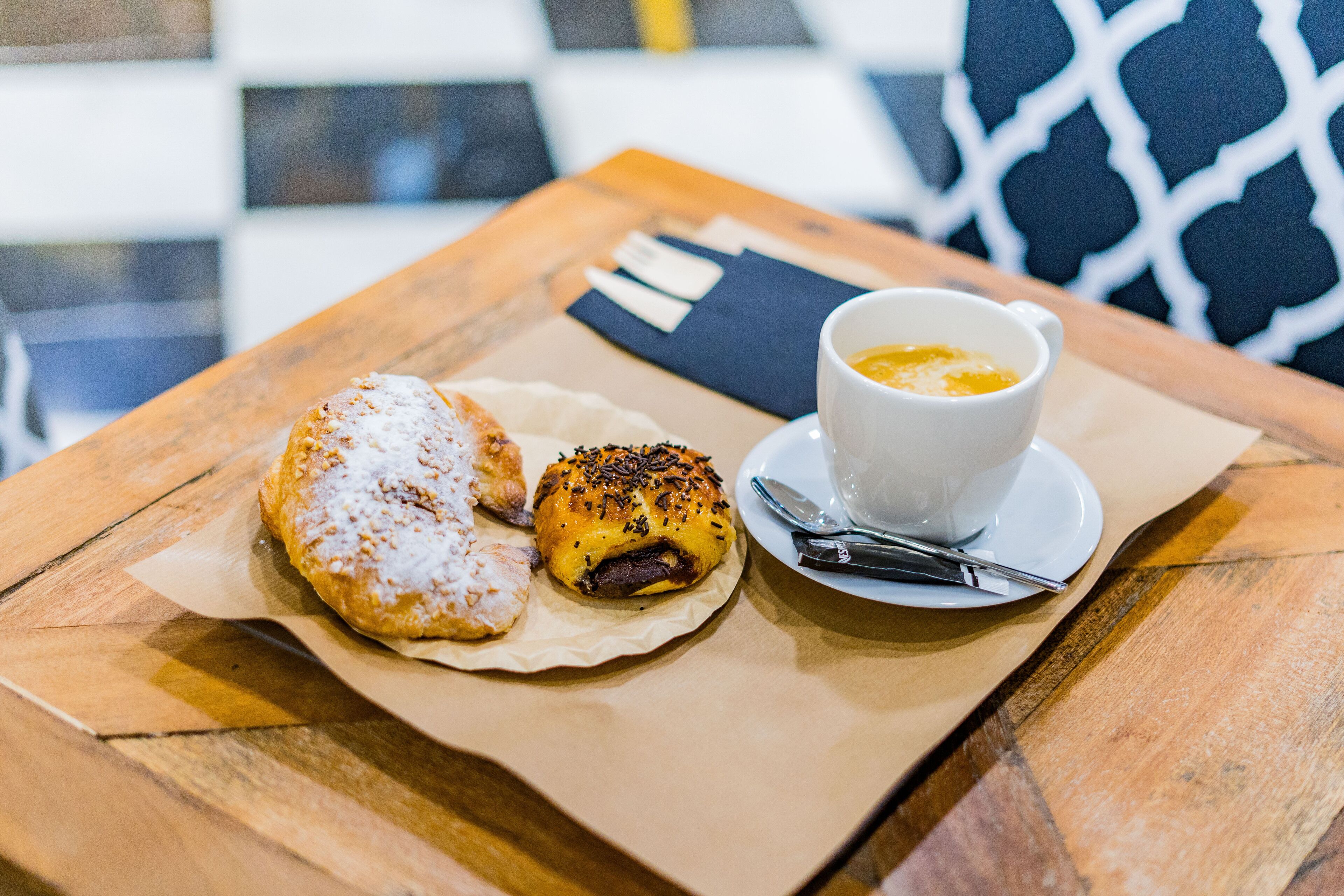 Una mesa con un pastel, una taza de café y una servilleta.