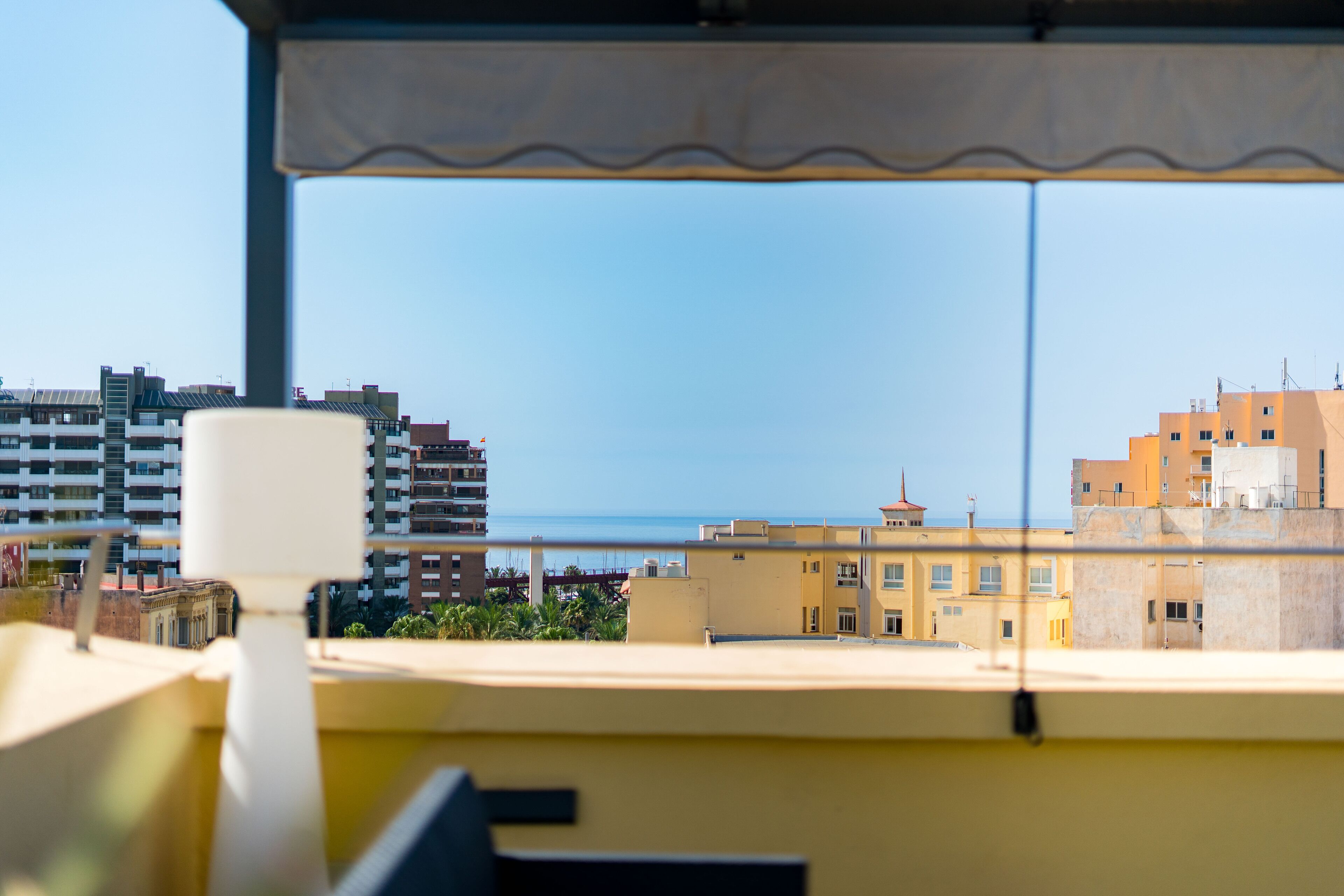 A view from a window overlooking a cityscape with buildings and a body of water.
