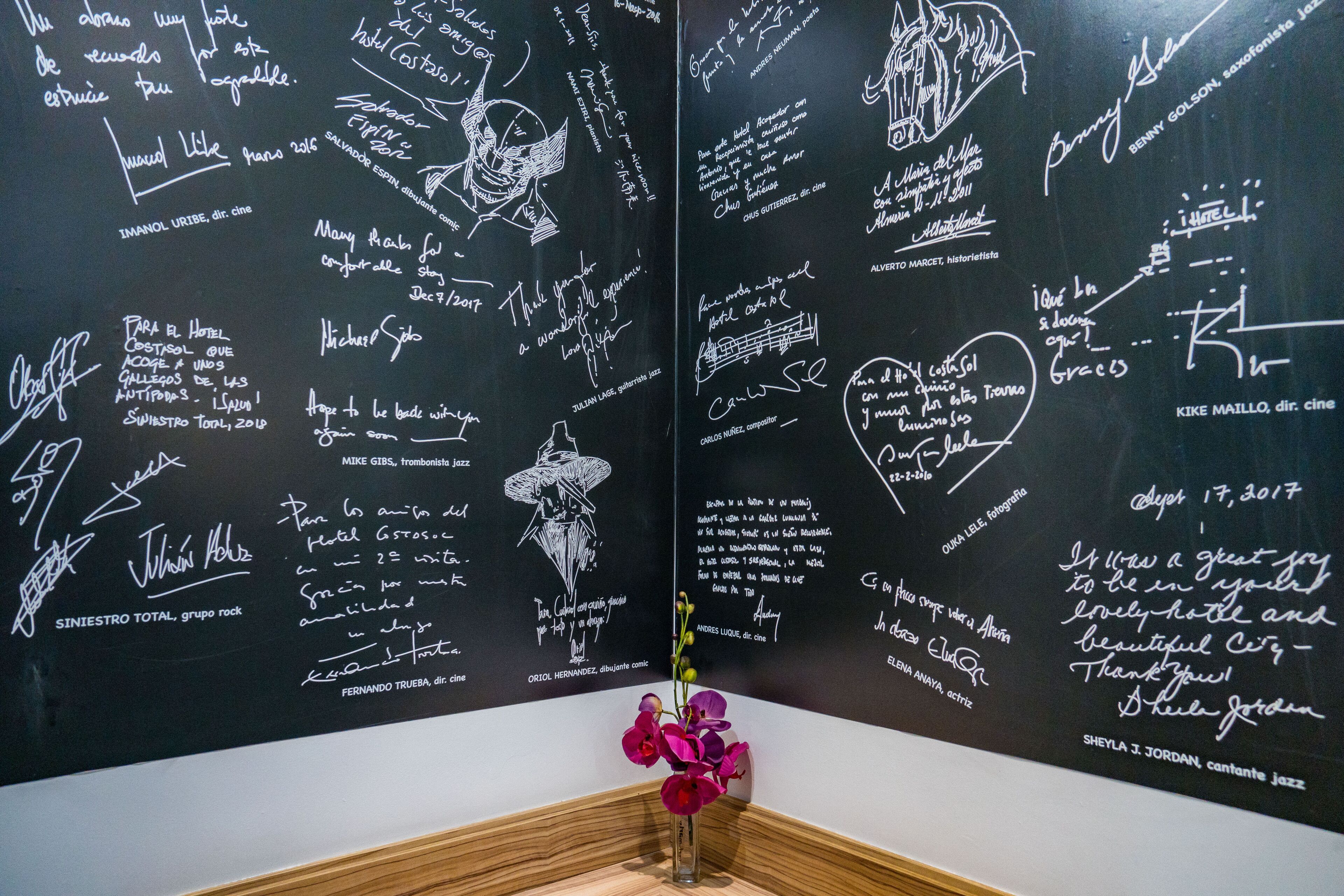 Een muur vol handtekeningen en berichten van verschillende mensen, waarschijnlijk een plek van betekenis of een feestelijke gelegenheid.