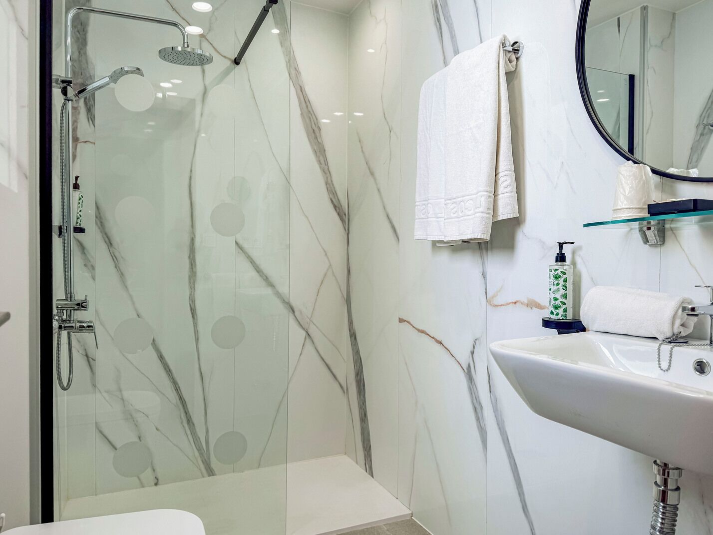 A modern bathroom with a glass-enclosed shower, a white sink, and a mirror.