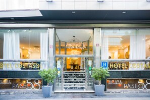 La entrada del Hotel CostaSol con fachada de vidrio, una escalera que conduce al vestíbulo y plantas en macetas a ambos lados.
