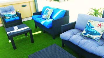 A patio area with wicker furniture, including a sofa and chairs, and a small table.