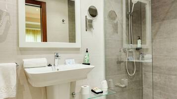 Un baño moderno con cabina de ducha de vidrio, un lavabo blanco y un espejo encima.