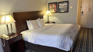 Una cama bien hecha con sábanas blancas, un cabecero de madera y dos lámparas de noche.