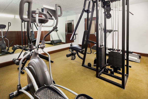 A gym with various exercise equipment, including an elliptical, a weight machine, and a cable machine.