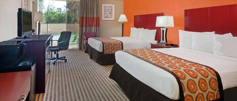 A hotel room with two beds, a desk with a computer, a chair, and a TV.