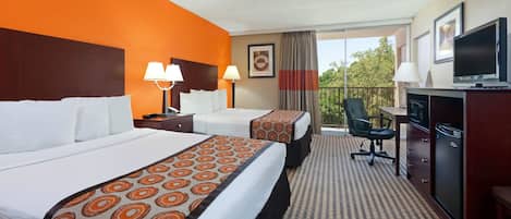 A hotel room with two beds, a desk, a television, and a balcony with a chair.