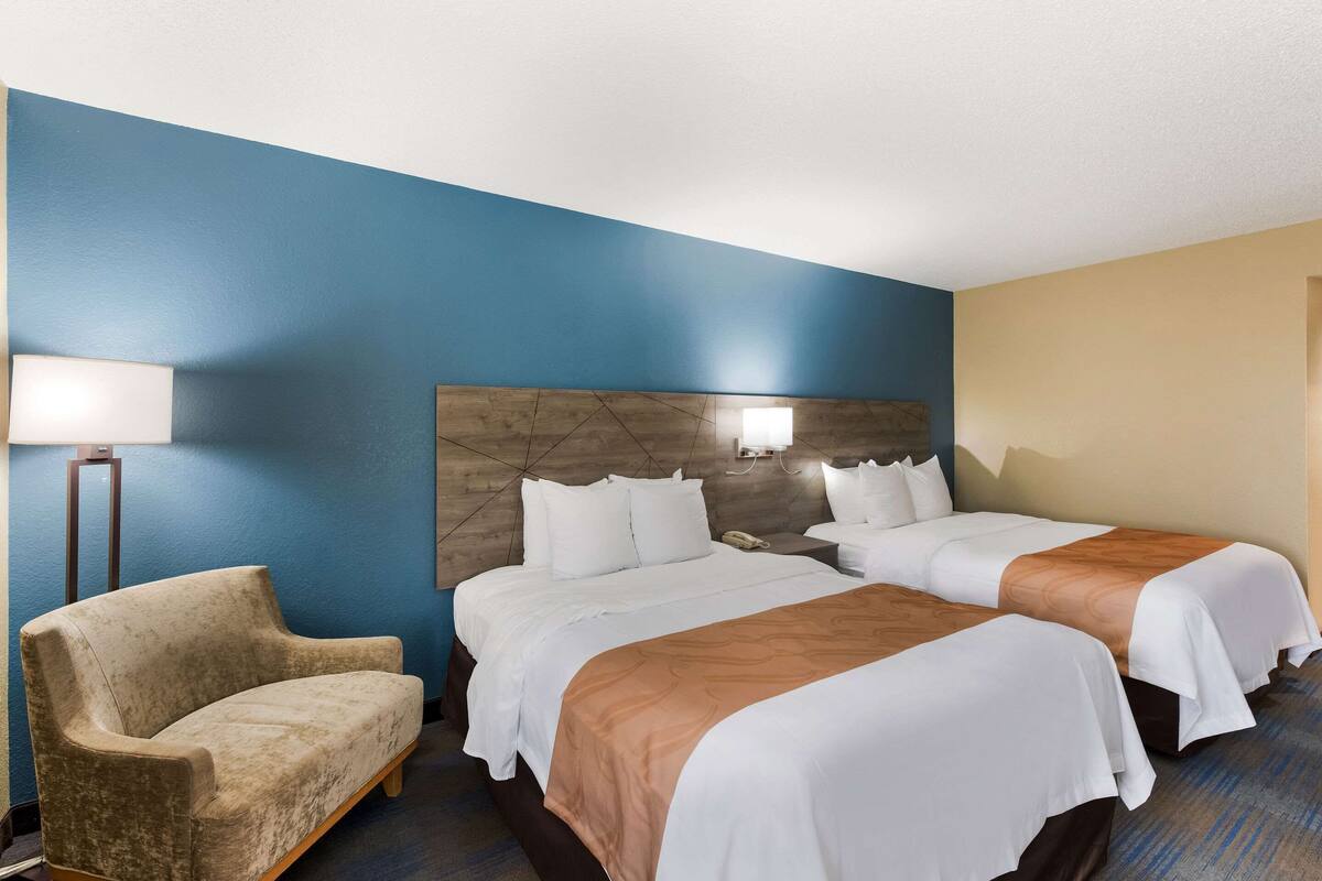 Una habitación de hotel con dos camas, un sofá y una lámpara.