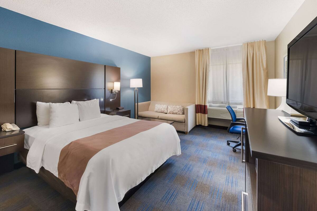 Una habitación de hotel con una cama grande, un sofá, un escritorio y un televisor.