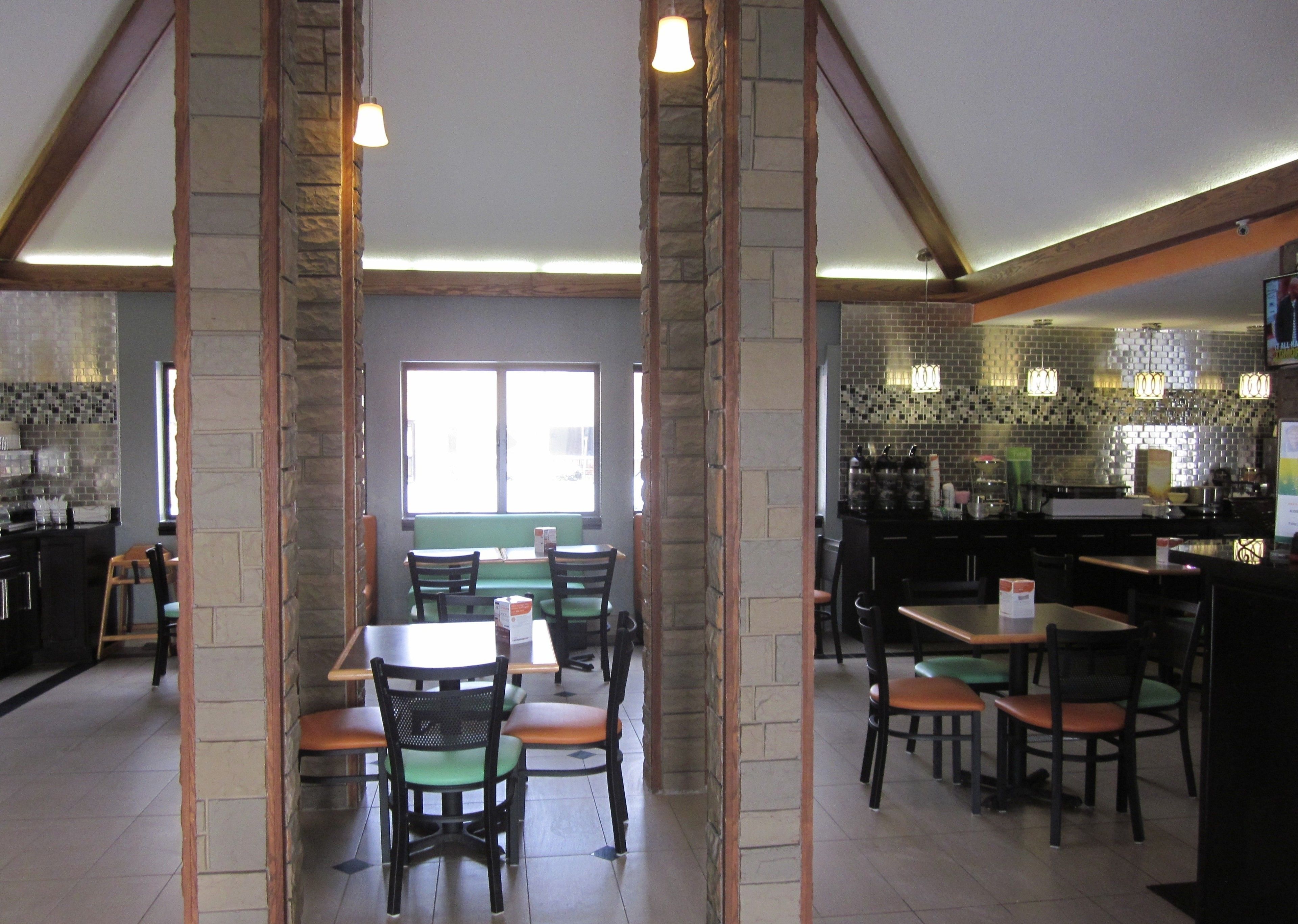 A restaurant with stone walls, wooden beams, and a mix of seating arrangements including tables and booths.