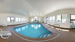 Una piscina interior con agua cristalina, rodeada de paredes con ventanas.