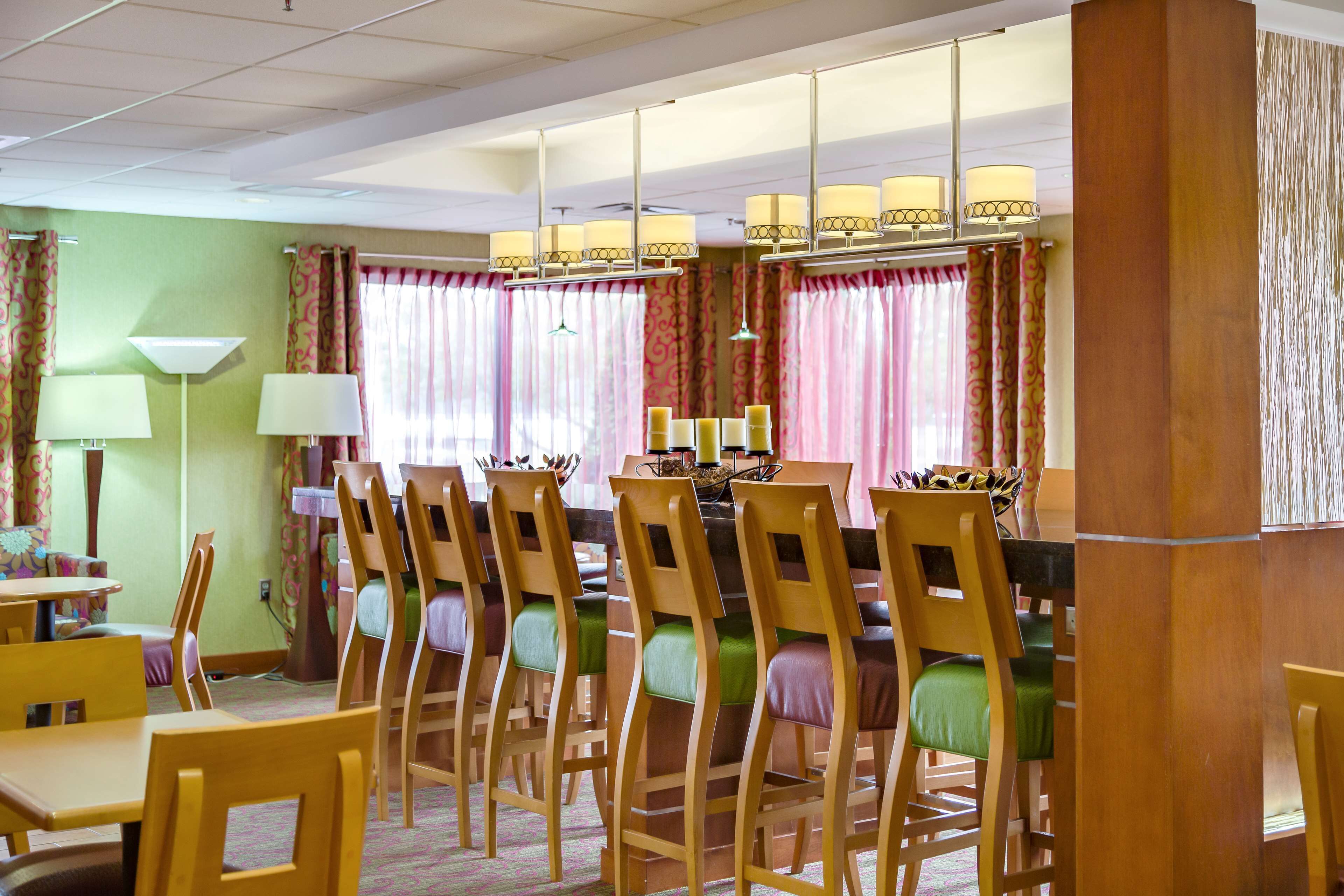 A dining area with wooden chairs and tables, a chandelier, and patterned curtains.