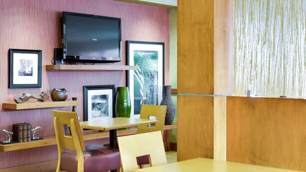 Ein Restaurant mit Holztischen, einem flachbildfernseher an der Wand und gerahmten Bildern auf den Regalen.