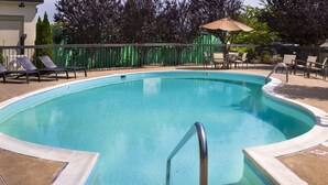 Ein Schwimmbecken mit Liegestühlen und einer überdachten Sitzgelegenheit.