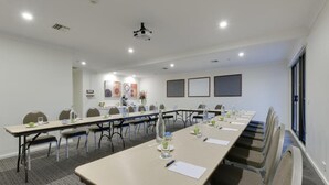 A conference room with long tables, chairs, and a projector screen. - Tall Trees Ainslie Motel (Ainslie)