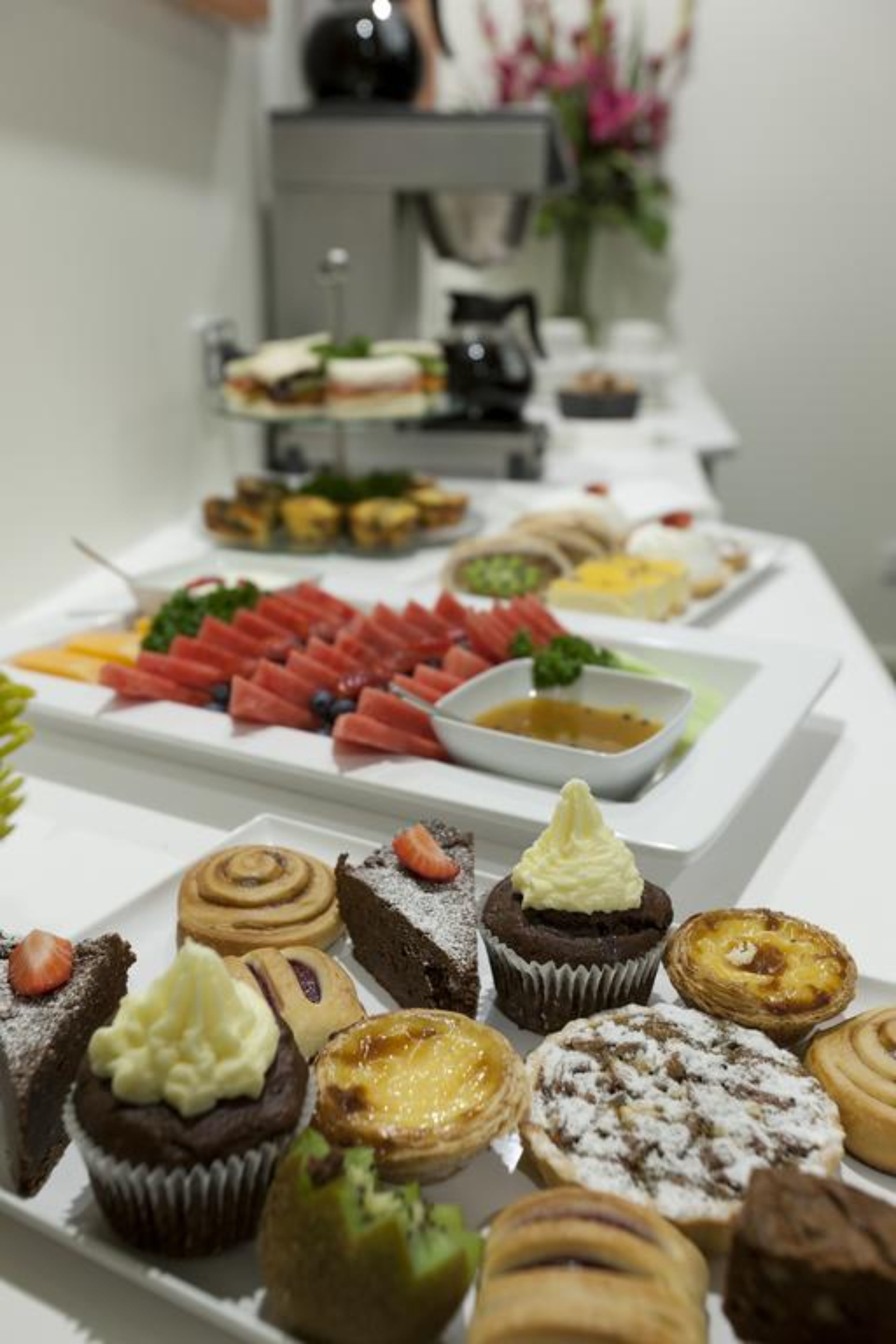 A buffet table with various pastries, fruits, and desserts.