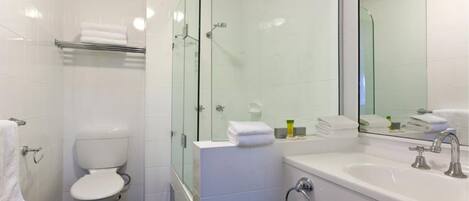 Une salle de bain moderne avec une douche à parois de verre, des toilettes blanches, un lavabo avec un miroir et un porte-serviettes.