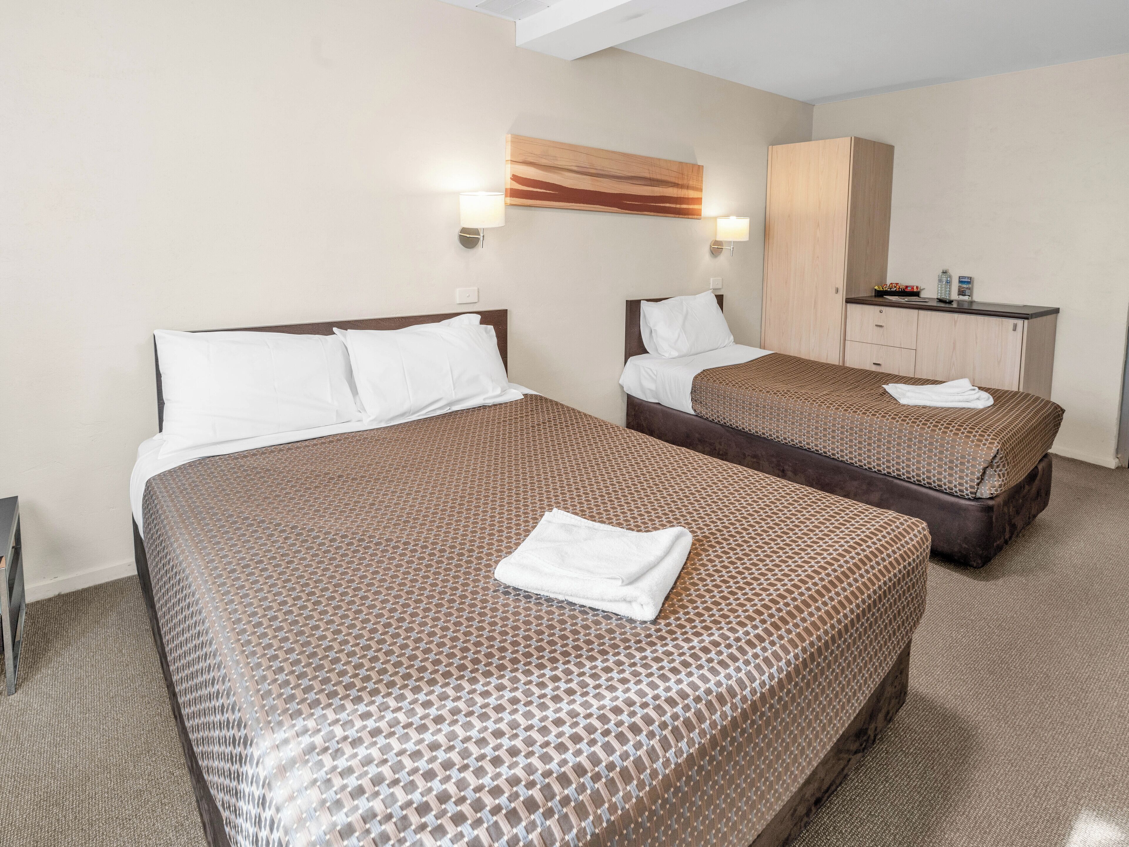 Una habitación de hotel con dos camas, un armario y un escritorio.