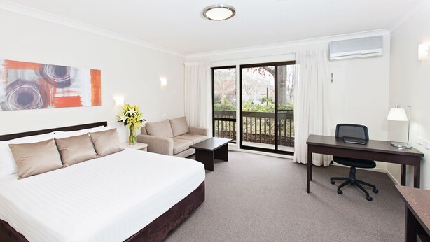 A hotel room with a bed, a sofa, a desk, and a view of the outdoors. - Tall Trees Ainslie Motel (Ainslie)