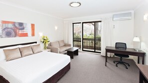 A hotel room with a bed, a sofa, a desk, and a view of the outdoors. - Tall Trees Ainslie Motel (Ainslie)