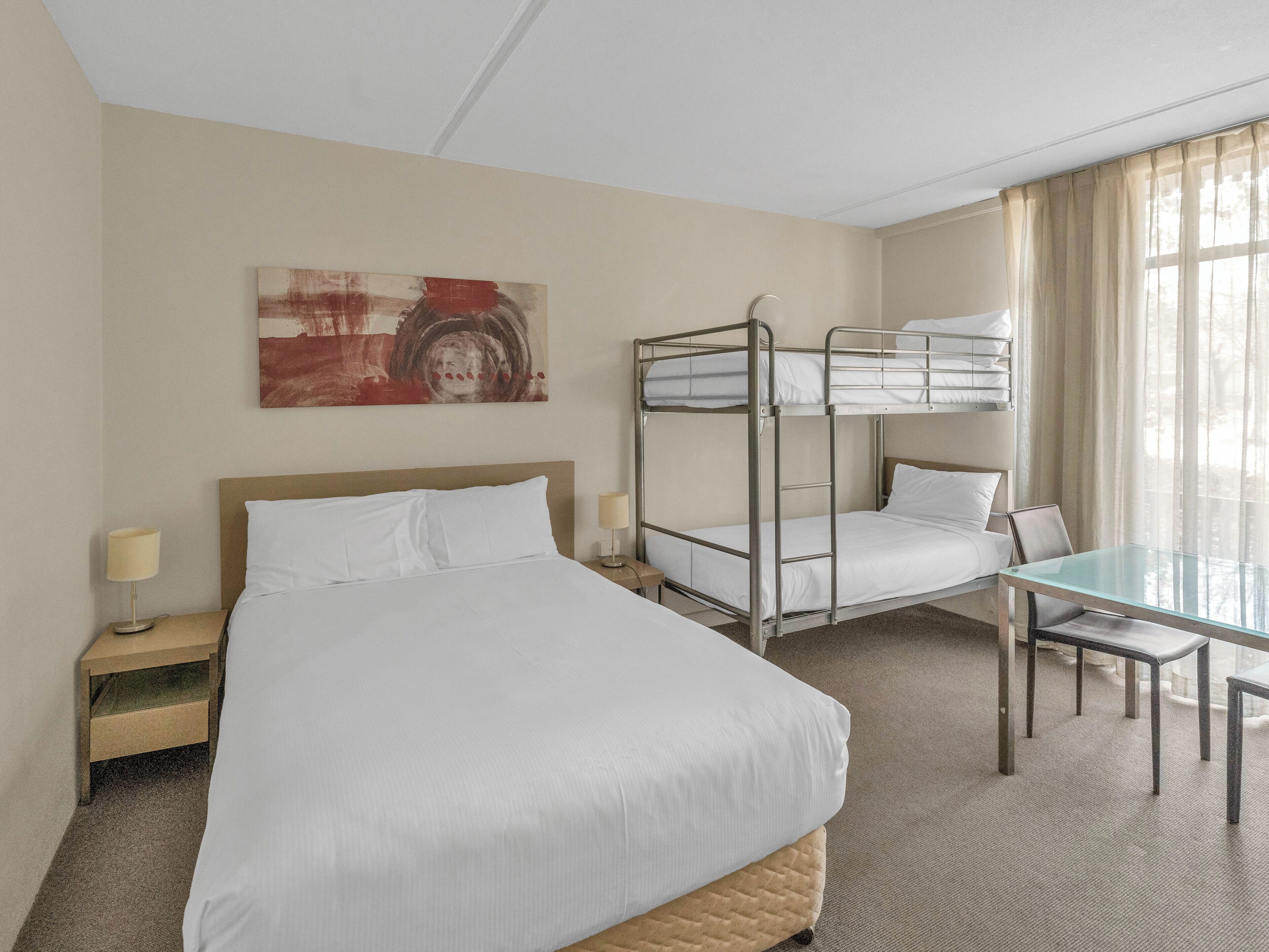 Habitación de hotel con literas, un escritorio y una silla.
