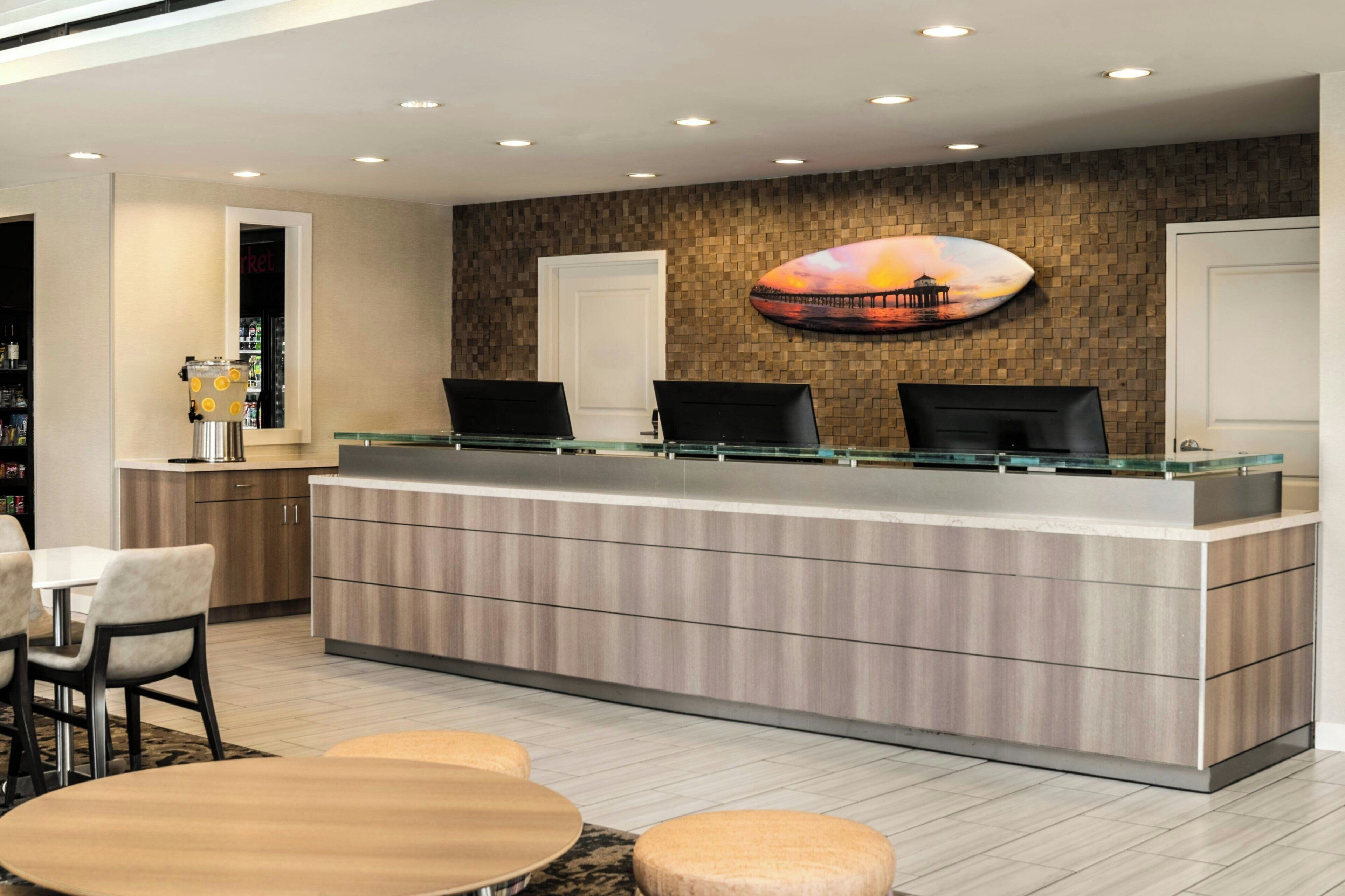 A reception area with a modern design, featuring a reception desk, seating area, and a wall-mounted artwork.