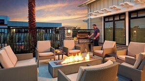 Une terrasse sur le toit, aménagée avec des meubles en osier, un foyer et un barbecue.