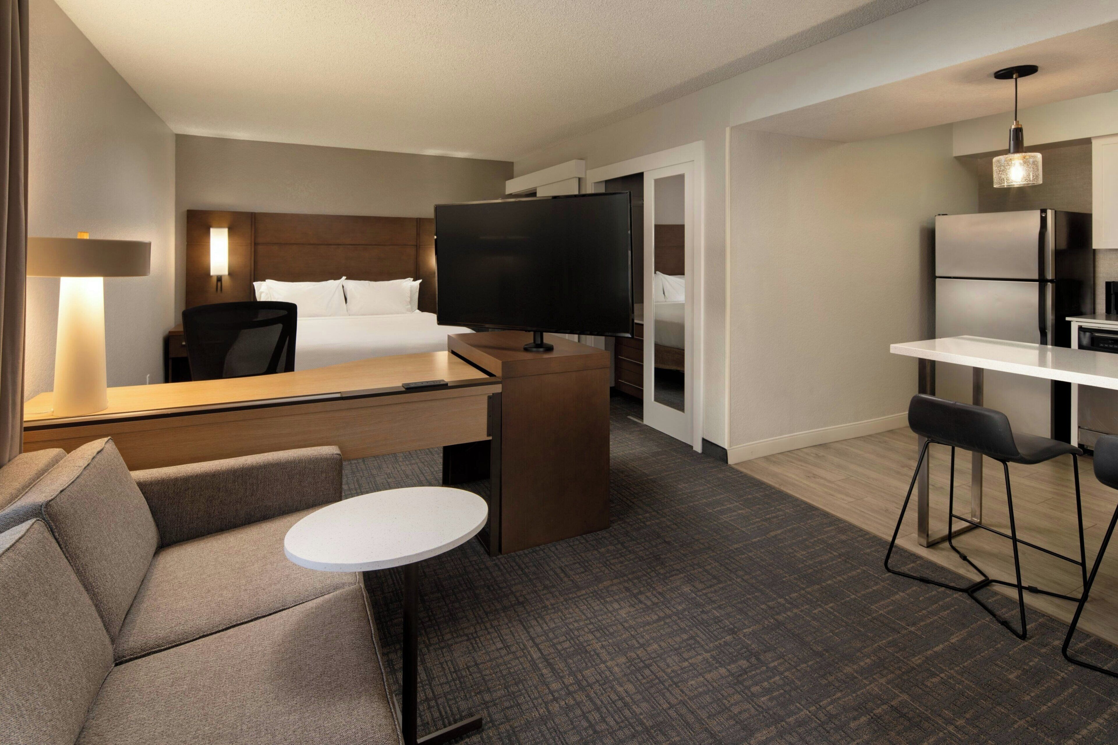A hotel room with a bed, a TV, a desk, a chair, and a small table.
