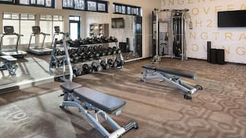 Un gimnasio con cintas de correr, mancuernas y máquinas de pesas.