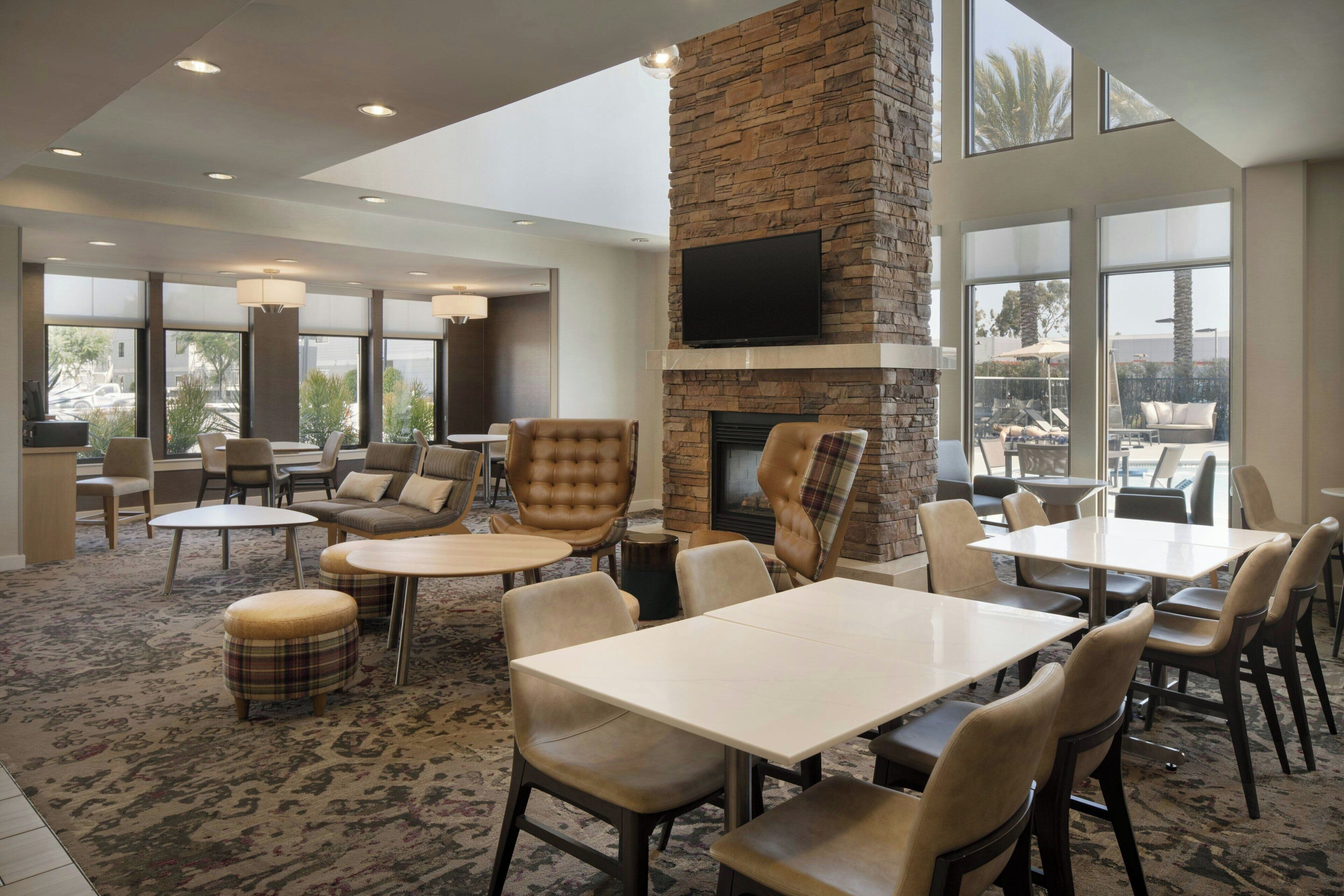 A spacious indoor area with multiple seating arrangements, a stone fireplace, and large windows offering views.