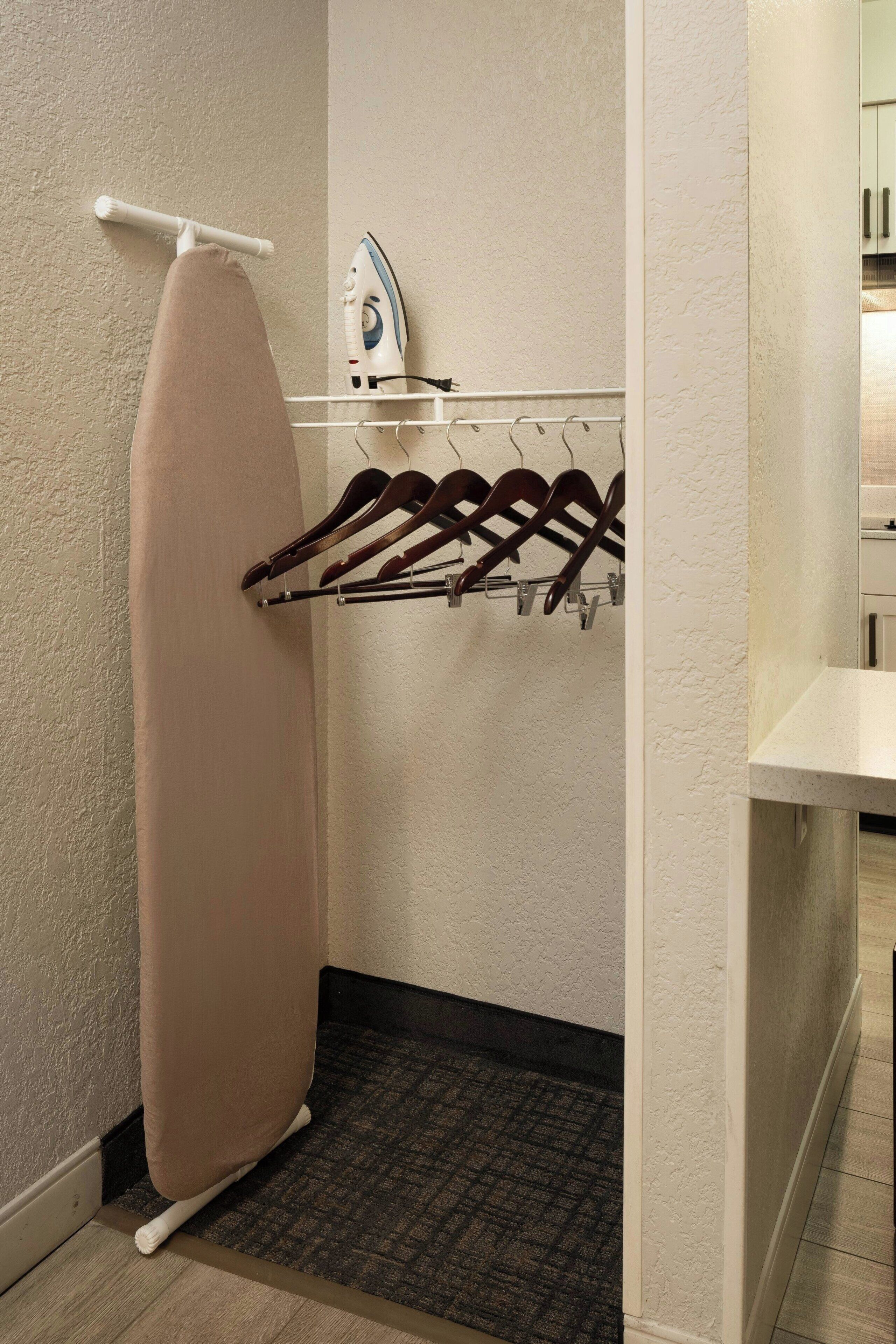 A laundry area with a hanging rack, an iron, and a towel rack.