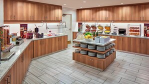 Une cuisine moderne avec des meubles en bois, un plan de travail en marbre et une variété d’aliments et d’appareils électroménagers.