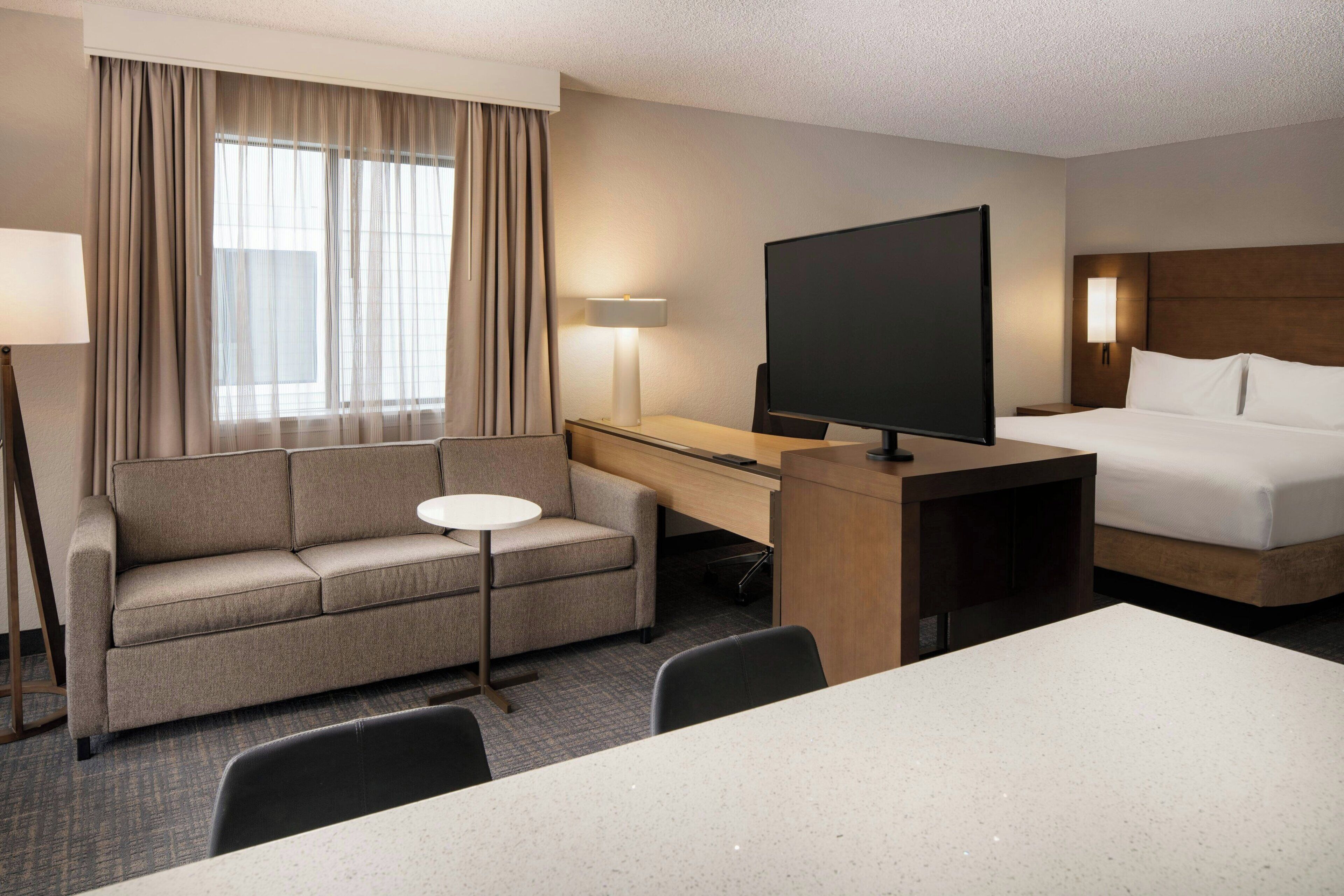 Une chambre d’hôtel équipée d’un canapé, d’un bureau, d’une télévision, d  ’un lit et d’une petite table.