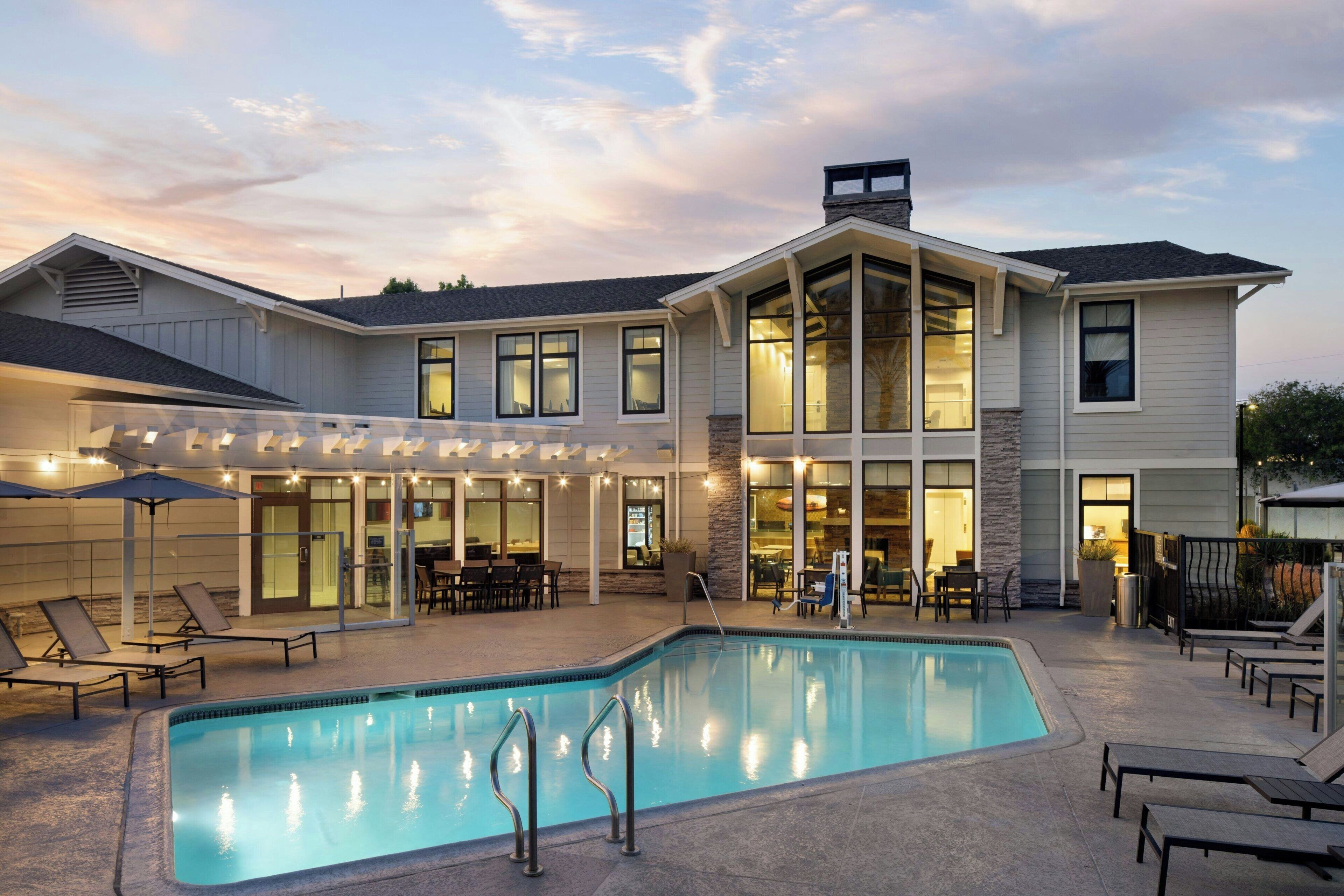 A two-story house with a swimming pool, outdoor seating, and a covered patio area.